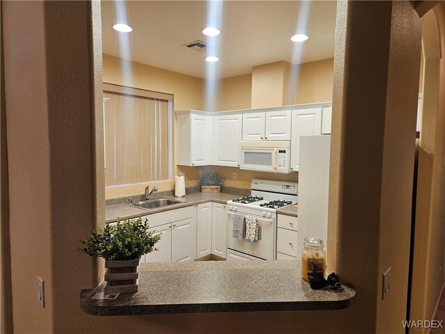 kitchen featuring recessed lighting, visible vents, white cabinets, a sink, and white appliances