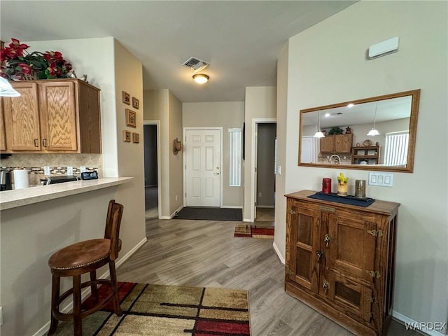 kitchen featuring wood finished floors, visible vents, light countertops, tasteful backsplash, and decorative light fixtures