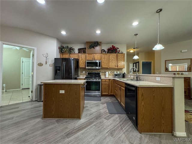 kitchen with hanging light fixtures, black appliances, light countertops, and a sink