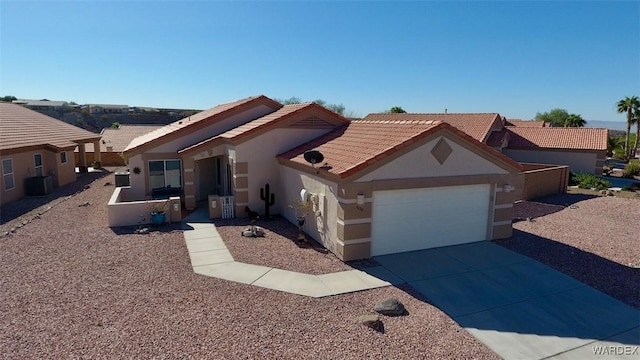 view of front facade with stucco siding, an attached garage, central AC, driveway, and a tiled roof