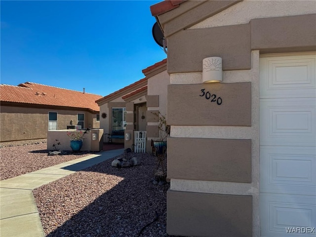 property entrance featuring a tiled roof, an attached garage, and stucco siding