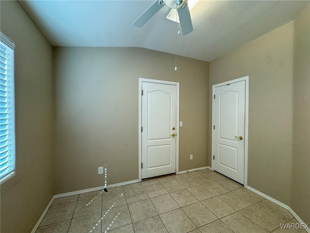 spare room with ceiling fan, vaulted ceiling, baseboards, and light tile patterned floors