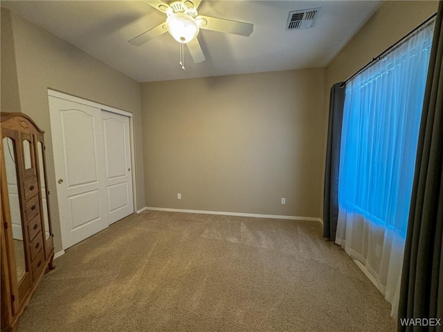 unfurnished bedroom with light carpet, baseboards, visible vents, and ceiling fan