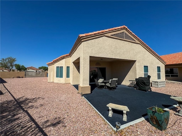 rear view of property with stucco siding, a fenced backyard, a tile roof, and a patio