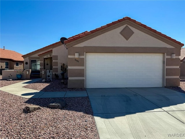 view of front facade featuring a garage, concrete driveway, a tiled roof, and stucco siding