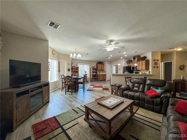 living room with light wood-style floors, visible vents, and ceiling fan with notable chandelier