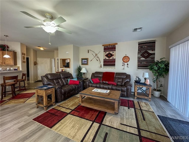 living room featuring light wood finished floors, ceiling fan, and visible vents