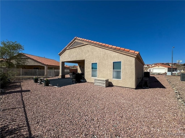 rear view of house featuring a patio area, a tile roof, fence, and stucco siding