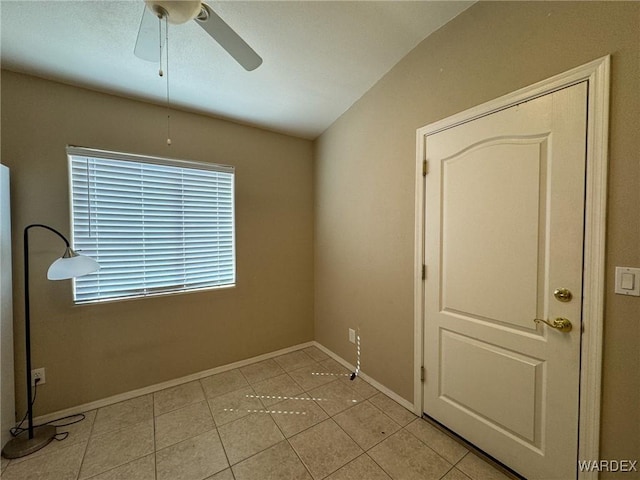 unfurnished room featuring lofted ceiling, light tile patterned flooring, ceiling fan, and baseboards