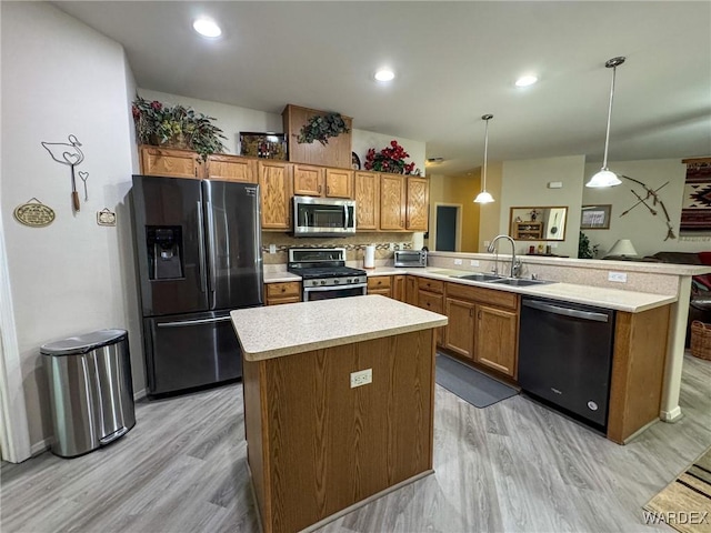 kitchen featuring decorative light fixtures, stainless steel appliances, light countertops, a sink, and a peninsula