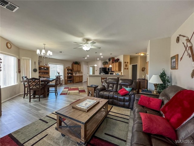 living room with light wood-style floors, baseboards, visible vents, and ceiling fan with notable chandelier