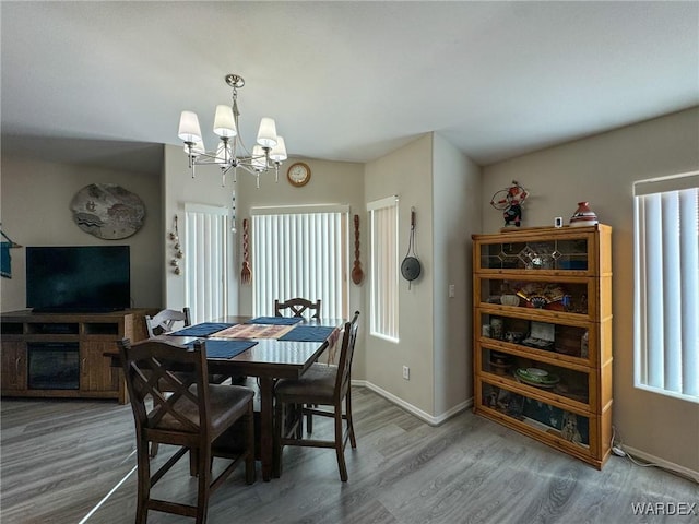 dining area featuring a notable chandelier, baseboards, and wood finished floors