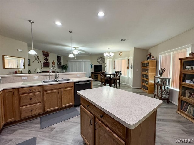 kitchen featuring black dishwasher, light countertops, a sink, and a center island