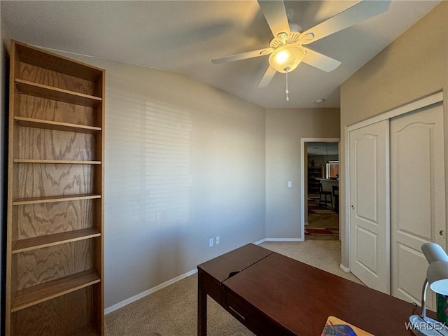 office area featuring ceiling fan, baseboards, and light colored carpet