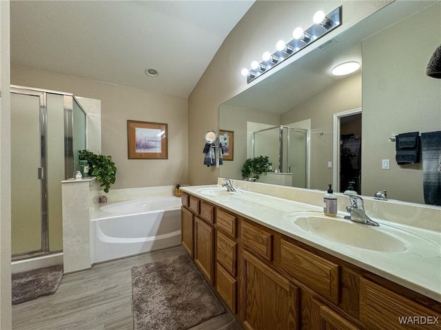 bathroom featuring a garden tub, a stall shower, and a sink