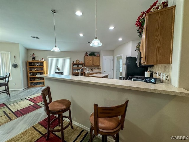 3020 Siena Dr, Bullhead City, AZ 86442 - kitchen featuring light countertops, hanging light fixtures, backsplash, brown cabinets, and a kitchen bar