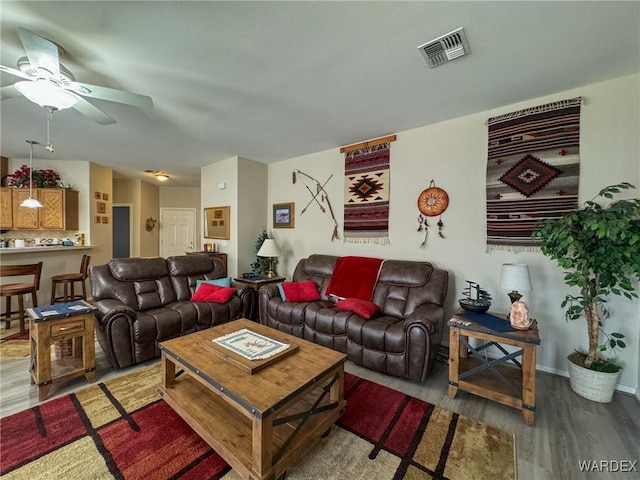 living room featuring a ceiling fan, baseboards, visible vents, and wood finished floors