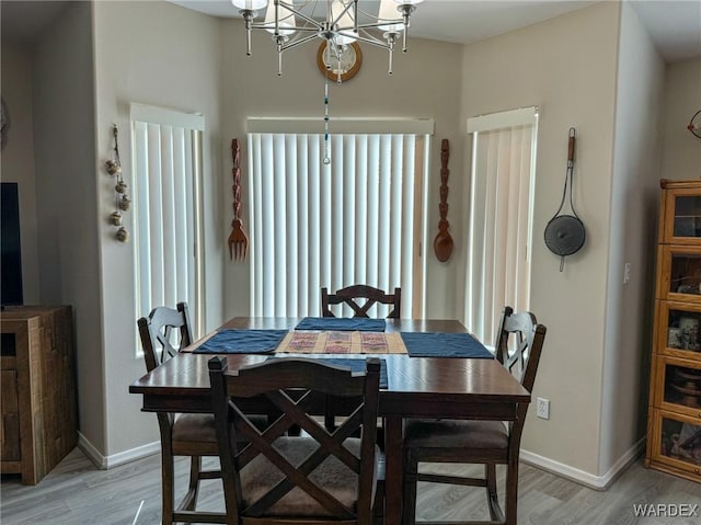 dining room with light wood finished floors, baseboards, and an inviting chandelier