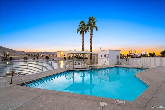 211 Moser Ave Unit 104, Bullhead City, AZ 86429 - pool at dusk featuring a mountain view, a patio, a community pool, and fence