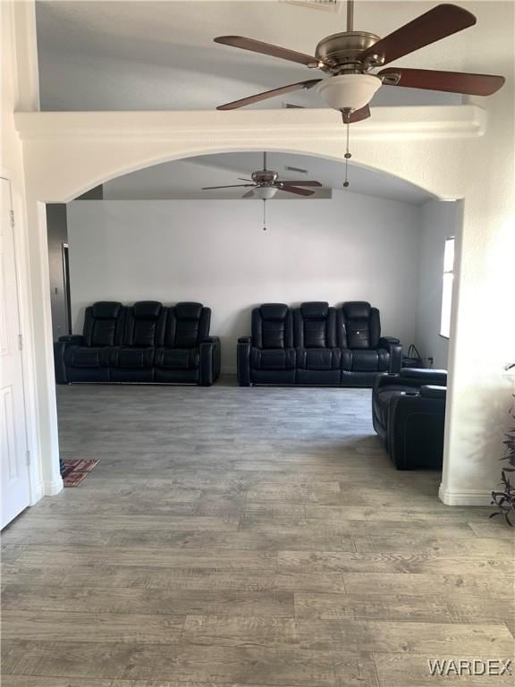 living area featuring lofted ceiling, arched walkways, and wood finished floors