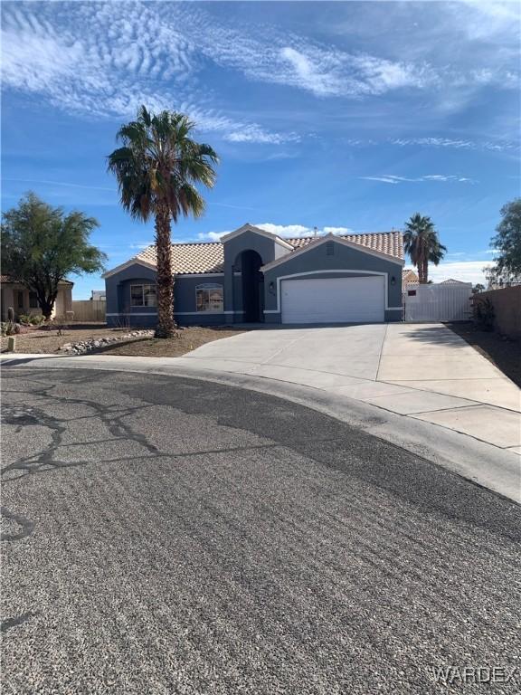 view of front of home with driveway, an attached garage, a tile roof, and stucco siding