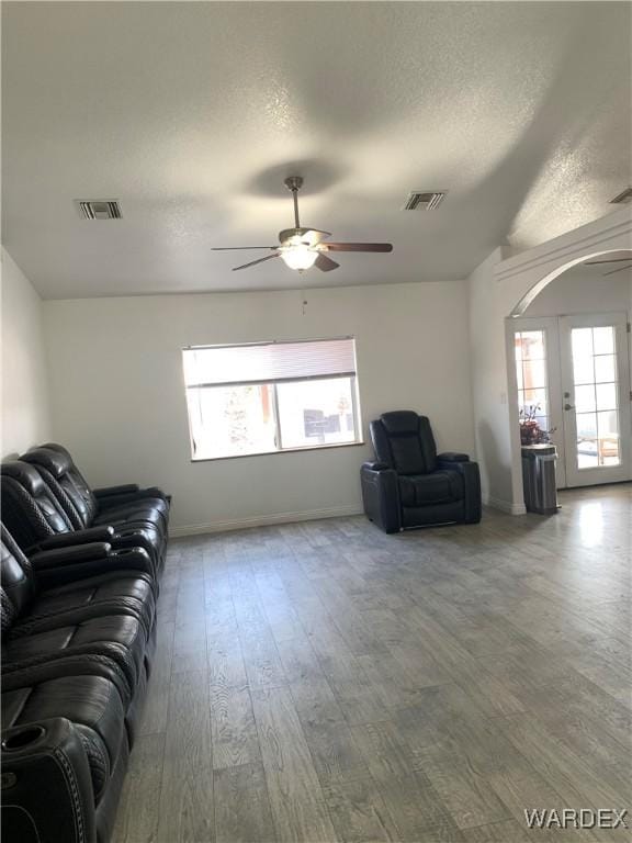 living room featuring a textured ceiling, visible vents, wood finished floors, and french doors