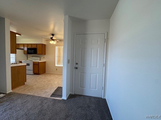 1280 Mohave Dr Unit 8A, Bullhead City, AZ 86442 - kitchen featuring a ceiling fan, electric range, black microwave, light carpet, and brown cabinets