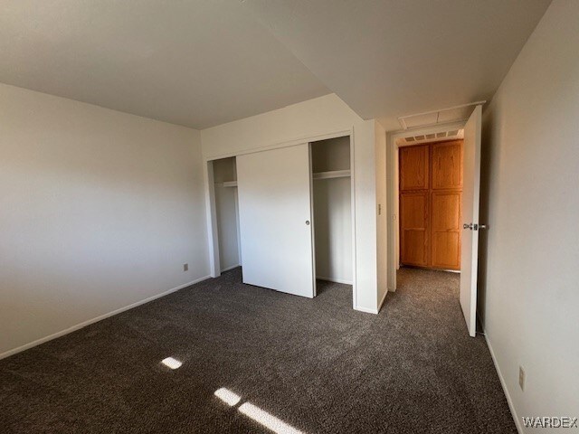 1280 Mohave Dr Unit 8A, Bullhead City, AZ 86442 - unfurnished bedroom featuring a closet, visible vents, dark carpet, and baseboards