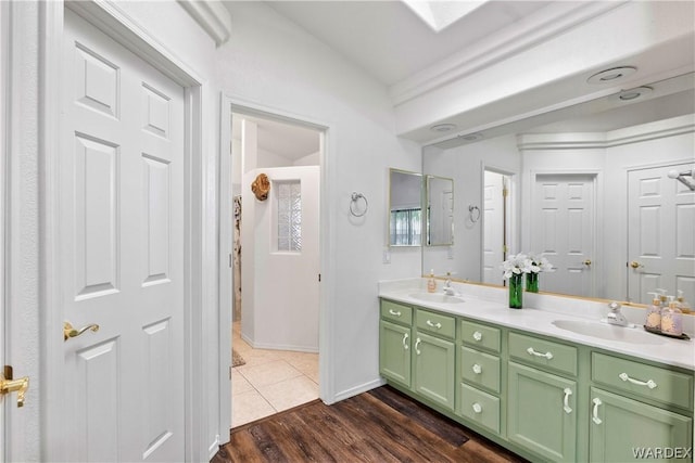 bathroom featuring double vanity, baseboards, a sink, and wood finished floors