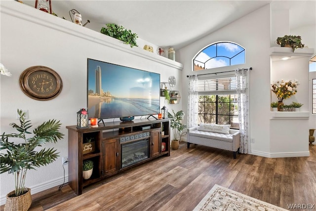 living area featuring high vaulted ceiling, baseboards, and wood finished floors