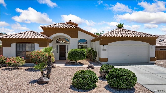 mediterranean / spanish-style home with concrete driveway, a tiled roof, an attached garage, and stucco siding