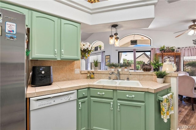 kitchen with a sink, green cabinets, freestanding refrigerator, dishwasher, and decorative light fixtures