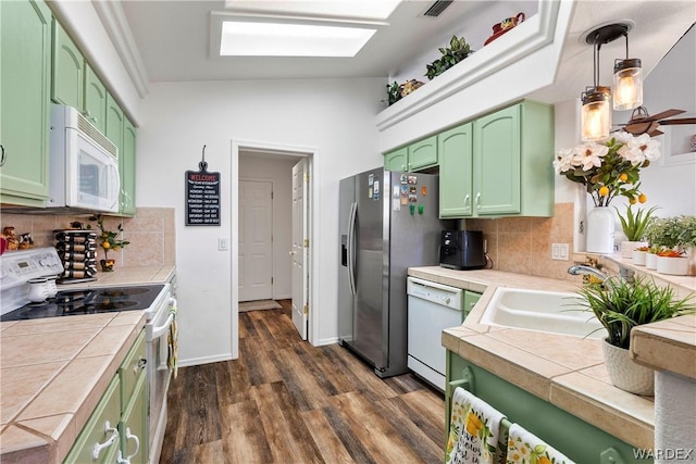 kitchen with white appliances, tile counters, green cabinetry, and decorative light fixtures