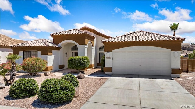 mediterranean / spanish-style house with an attached garage, driveway, a tile roof, and stucco siding