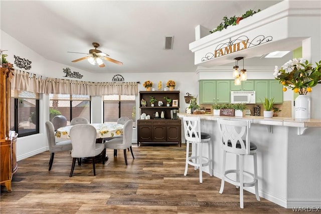 dining area with a ceiling fan, baseboards, visible vents, and dark wood-type flooring