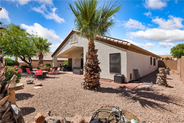 back of house with a fire pit, a fenced backyard, a tiled roof, a patio area, and stucco siding