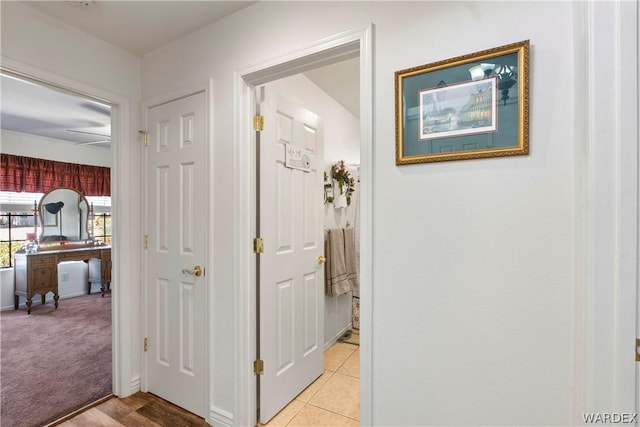 hall with light carpet and light tile patterned flooring