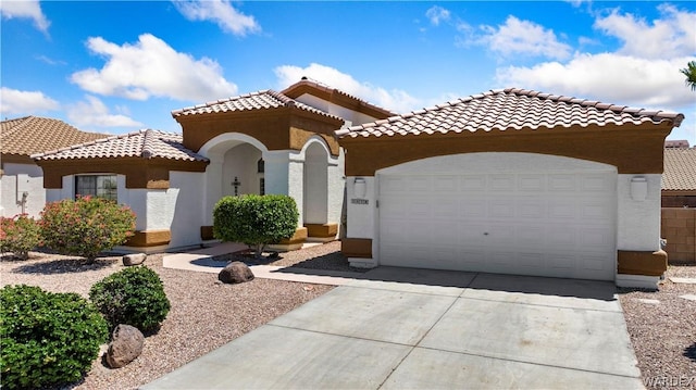 mediterranean / spanish-style house with an attached garage, a tiled roof, concrete driveway, and stucco siding