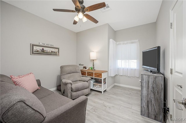 living room featuring light wood-style flooring, a ceiling fan, visible vents, and baseboards