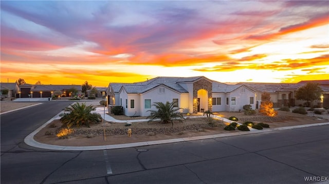 view of front of property featuring driveway, a tiled roof, a residential view, and stucco siding