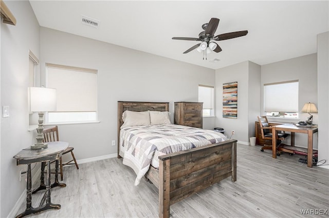 bedroom featuring a ceiling fan, light wood-style flooring, visible vents, and baseboards