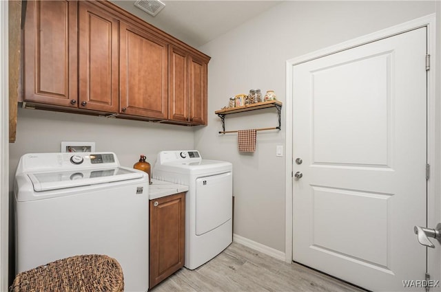 washroom with visible vents, baseboards, washer and dryer, cabinet space, and light wood finished floors