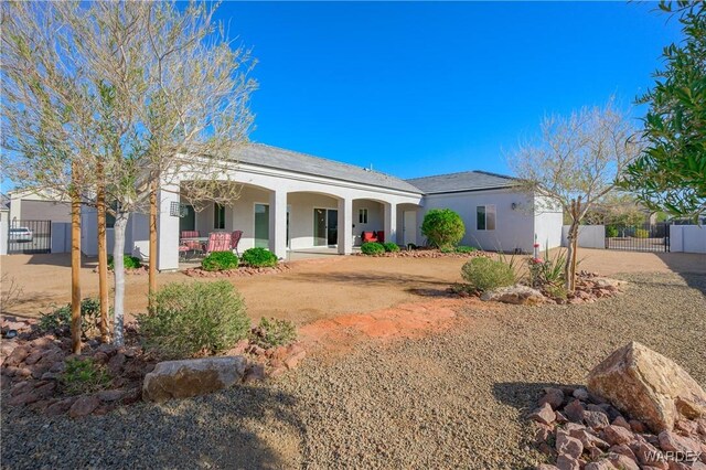 back of house with a gate, fence, a porch, and stucco siding