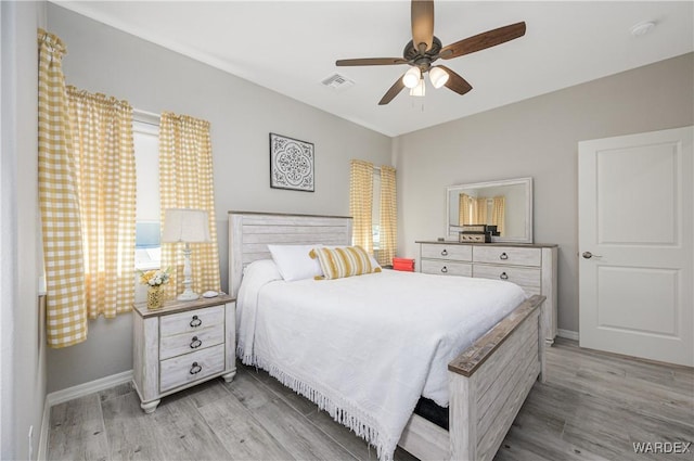 bedroom featuring light wood-style floors, visible vents, and baseboards