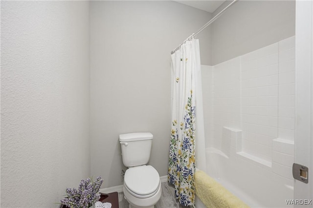 bathroom with baseboards, toilet, and shower / bath combo with shower curtain