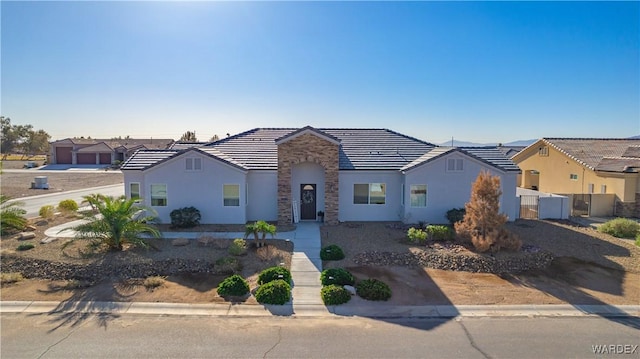 view of front of house featuring stone siding, a tile roof, a residential view, and stucco siding