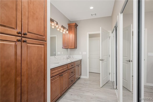 bathroom featuring a sink, double vanity, visible vents, and wood finished floors