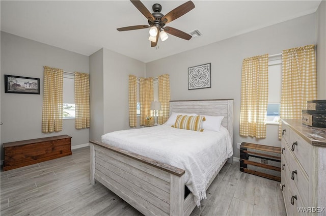 bedroom with light wood-style flooring, visible vents, ceiling fan, and baseboards