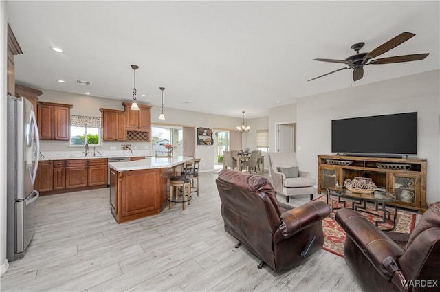 living area with recessed lighting, visible vents, light wood-style flooring, and ceiling fan with notable chandelier