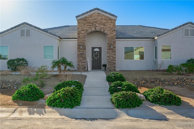 view of front of home with stone siding, a tile roof, and stucco siding